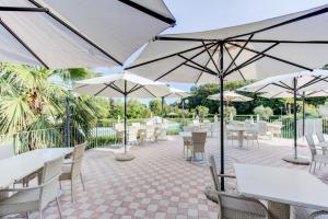 un patio con mesas, sillas y sombrillas en Monastero Resort & Spa - Garda Lake Collection en Soiano del Lago