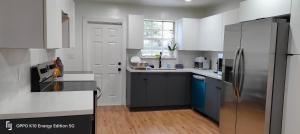 a kitchen with white cabinets and a stainless steel refrigerator at Edercozy in Miami