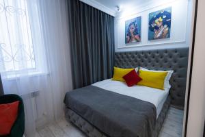 1 dormitorio con 1 cama con almohadas amarillas y rojas en Metelitsa Hotel, en Karagandá