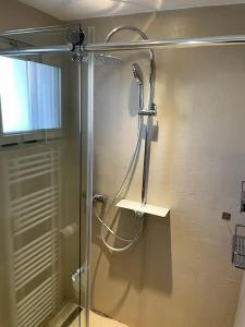 La salle de bains est pourvue d'une douche avec une porte en verre. dans l'établissement Appartement à 5 min à pied des plages, à Vallauris