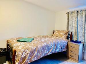 a bedroom with a bed and a wooden dresser with a bedspread at One Bedroom Apartment Wembley Stadium in London in London