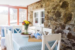 a dining room with a table with chairs and a stone wall at Pine Cottage Little Haven in Little Haven