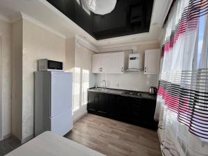 a kitchen with black cabinets and a white refrigerator at ЖК Алмалы напротив Алматы Арены 47-6 in Almaty