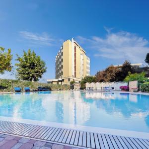 une grande piscine avec un bâtiment en arrière-plan dans l'établissement Hotel Colorado Cesenatico, à Cesenatico