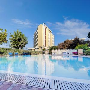 a large swimming pool with a building in the background at Hotel Colorado Cesenatico in Cesenatico