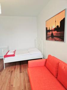 a white bed with a red couch in a room at City Studio Apartment for 4, near Sonnenallee in Berlin