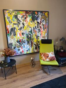 una silla amarilla en una habitación con un cuadro en la pared en Roxy’s Kabin, en Jelgava