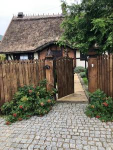 a small house with a wooden gate and a fence at REETDACH FERIENHAUS IN GĄSKI MIT GEPFLEGTEM GARTEN in Gąski