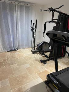 een kamer met een fitnessruimte met een loopband en fitnessapparatuur bij La pause 