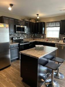 a kitchen with stainless steel appliances and a island with bar stools at Cozy Nest: Where Love Blossoms in Nashville