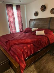 a bedroom with a bed with a red comforter and a window at Cozy Nest: Where Love Blossoms in Nashville