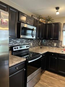 a kitchen with black cabinets and a microwave at Cozy Nest: Where Love Blossoms in Nashville