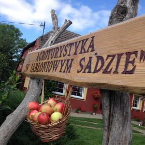 ein Schild mit einem Korb mit Äpfeln vor einem Haus in der Unterkunft Agroturystyka W Jabłoniowym Sadzie in Jeżyce