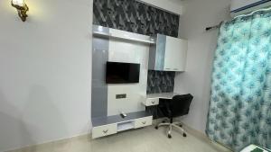 Habitación con escritorio, silla y TV. en Exotic studio en Ghaziabad