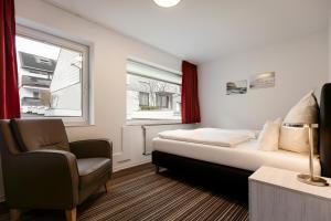 1 dormitorio con 1 cama, 1 silla y 1 ventana en Hotel Felsen-Eck en Helgoland