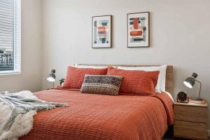 een bed met een oranje dekbed en twee foto's aan de muur bij Palm Cove condo in Atkinville