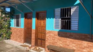 een blauw gebouw met houten deuren en een bank bij Suites do Sr Carlos in Ubatuba