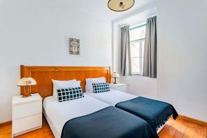 - une chambre avec un lit bleu et blanc et une fenêtre dans l'établissement Douradores Downtown Flat, à Lisbonne