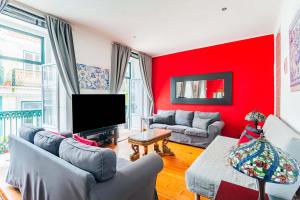 - un salon rouge avec des canapés et une télévision à écran plat dans l'établissement Douradores Downtown Flat, à Lisbonne