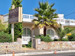 a sign in front of a house with a palm tree at Perla Beach in Agia Marina Nea Kydonias