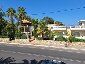 a street in front of a building with palm trees at Perla Beach in Agia Marina Nea Kydonias