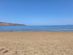 a person standing in the water on a beach at Perla Beach in Agia Marina Nea Kydonias