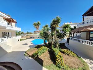 a palm tree in a yard next to a swimming pool at Perla Beach in Agia Marina Nea Kydonias