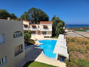 an apartment with a swimming pool next to a building at Perla Beach in Agia Marina Nea Kydonias