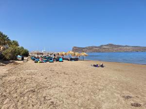 a group of people laying on a beach with umbrellas at Perla Beach in Agia Marina Nea Kydonias