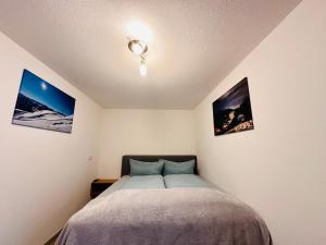 a bedroom with a bed and three pictures on the wall at Apartment Span in Fulpmes
