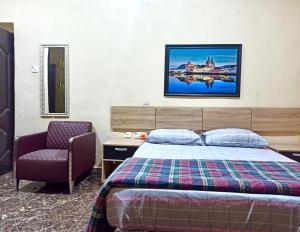 1 dormitorio con 1 cama y 1 silla en Bravo Apartment, Awka, en Akwa