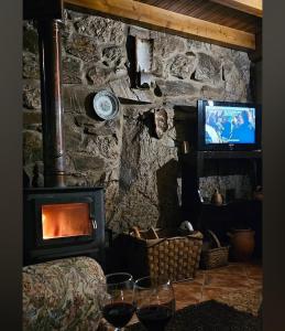 a living room with a fireplace and a tv at Quinta do Pé Longo - Serra da Estrela in Cortes do Meio