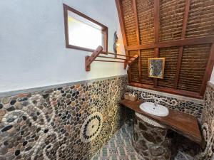 ein Bad mit einem Waschbecken und einem Fenster in der Unterkunft Sumatra Orangutan Treks Villa in Timbanglawang
