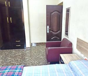 Zimmer mit 2 Betten, einem Sofa und einer Tür in der Unterkunft Bravo Apartment, Awka in Akwa