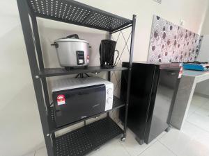 ein schwarzes Regal mit einer Mikrowelle und einem Toaster in der Unterkunft HOMESTAY DE’AMRIZ in KAPAR-MERU-KLANG-PUNCAK ALAM-SHAH ALAM in Kapar