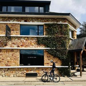 a man riding a bike in front of a building at Le Coffee Ride Cycling Cafe in Stavelot