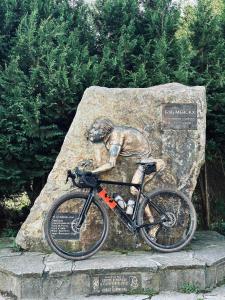 un vélo garé à côté d'un rocher avec une statue dans l'établissement Le Coffee Ride Cycling Cafe, à Stavelot