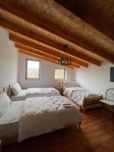 two beds in a room with wooden ceilings at Xhaferri Guesthouse in Çorovodë
