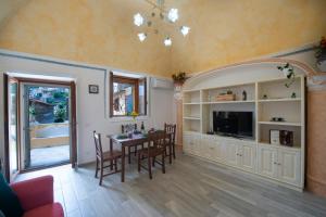 ein Wohnzimmer mit einem Tisch, Stühlen und einem TV in der Unterkunft Amore Rentals - Casa Barbera B in Positano