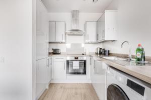 a white kitchen with white cabinets and a dishwasher at Spacious 1 BR apt w 2 king bed by Tent serviced apartments in Farnborough