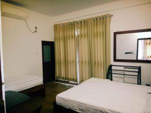 a bedroom with two beds and a window with curtains at Home Stay Resort in Nilaveli
