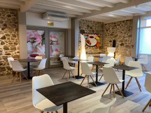 Cette chambre est dotée de tables, de chaises et d'un mur en pierre. dans l'établissement The Originals City, Hôtel Le Boeuf Rouge, Saint-Junien, à Saint-Junien