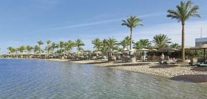 a beach with umbrellas and palm trees and water at Zahabia Hotel & Beach Resort in Hurghada