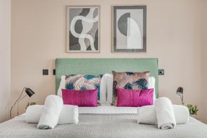 um quarto com uma cama com almofadas cor-de-rosa em Modern 1 BR apt near town centre by Tent serviced apartments em Egham