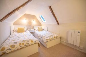 two beds in a small room with a attic at Vela Art Gallery - Holiday Apartment in Saxmundham