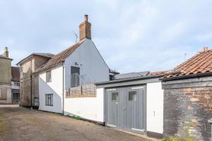 a white house with a grey garage at Vela Art Gallery - Holiday Apartment in Saxmundham