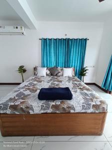 a bedroom with a large bed with blue curtains at Beach wave villa in Tirupporūr