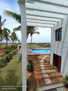 a white house with a pathway leading to a swimming pool at Beach wave villa in Tirupporūr