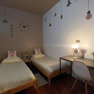 Habitación con 2 camas, escritorio y reloj en la pared. en Melon Hub ใกล้สนามบินสุวรรณภูมิ, en Ban Bang Toei (1)
