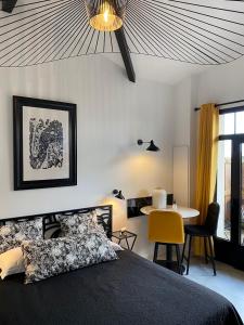 1 dormitorio con 1 cama y 1 mesa con silla amarilla en Hôtel particulier - Les lodges du Bassin d'Arcachon- Petit-déjeuner sur demande- Prestations haut de gamme en Gujan-Mestras